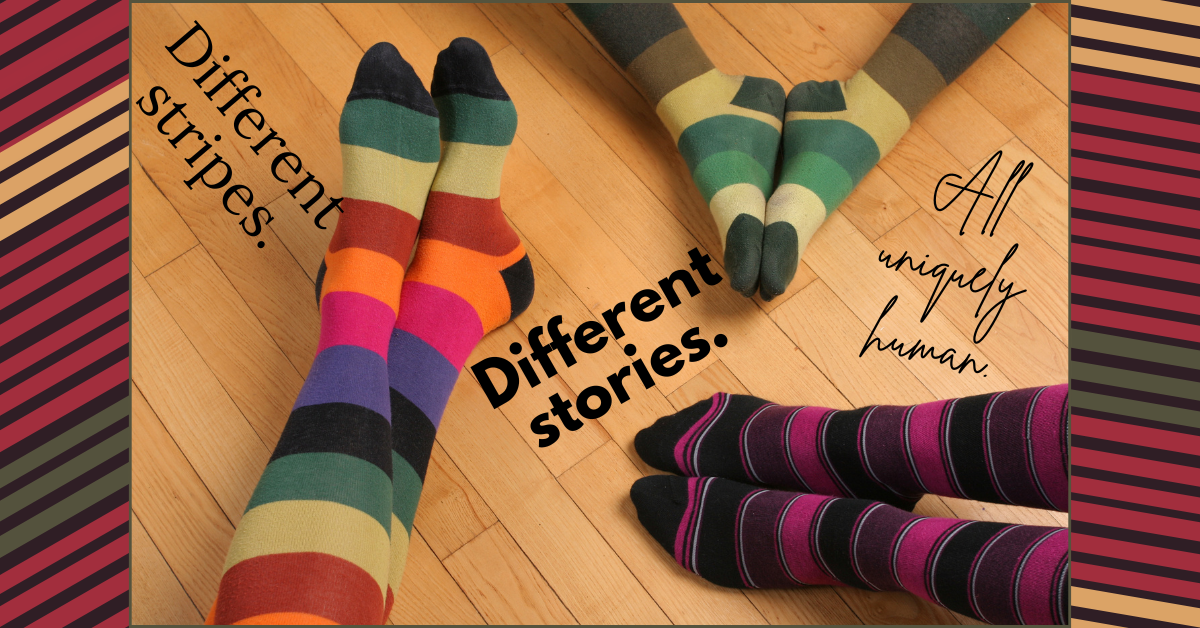 Three pairs of feet wearing colorful, striped socks rest on a wooden floor, each pair with a different pattern. Text on the image reads: “Different stripes. Different stories. All uniquely human.” The image celebrates individuality, diversity, and shared humanity.