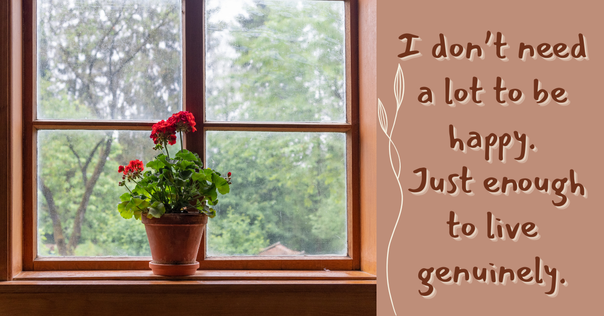 A terracotta potted plant with vibrant red flowers sits on a wooden windowsill, framed by a window showing a soft, cloudy view of green trees outside. On the right side of the image, a quote reads: “I don’t need a lot to be happy. Just enough to live genuinely.” The background is a warm earthy tone with a delicate white vine graphic adding a peaceful, organic touch.