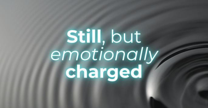 Dark ripples spread across a calm, black water surface, creating a hypnotic pattern of concentric waves. Centered over the image in glowing teal and white text are the words: “Still, but emotionally charged.” The scene evokes quiet intensity, symbolizing deep inner emotion beneath a composed exterior.