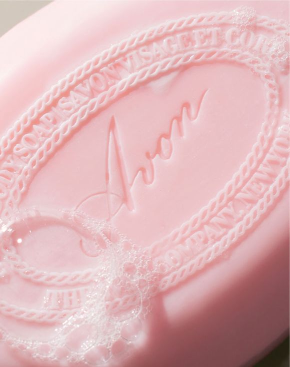 Close-up of a pink bar of Avon soap with delicate lather bubbles. The soap features vintage-style embossed branding, evoking a soft, nostalgic feel.