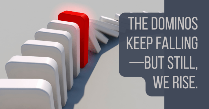 A row of white dominoes mid-collapse, stopped by a single upright red domino glowing slightly. Overlay reads: “The dominos keep falling—but still, we rise.”
