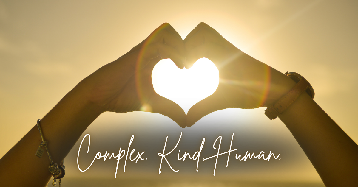 Hands form a heart in the golden light of the sun, symbolizing compassion, authenticity, and the beauty of being human.