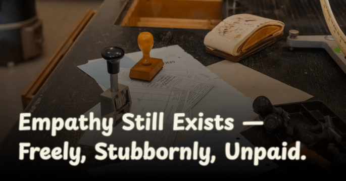 A wooden desk scattered with paperwork, ink stamps, and an open ledger. The text reads, “Empathy Still Exists — Freely, Stubbornly, Unpaid,” reflecting the humor and sincerity of an open letter to George Soros about unpaid activism.