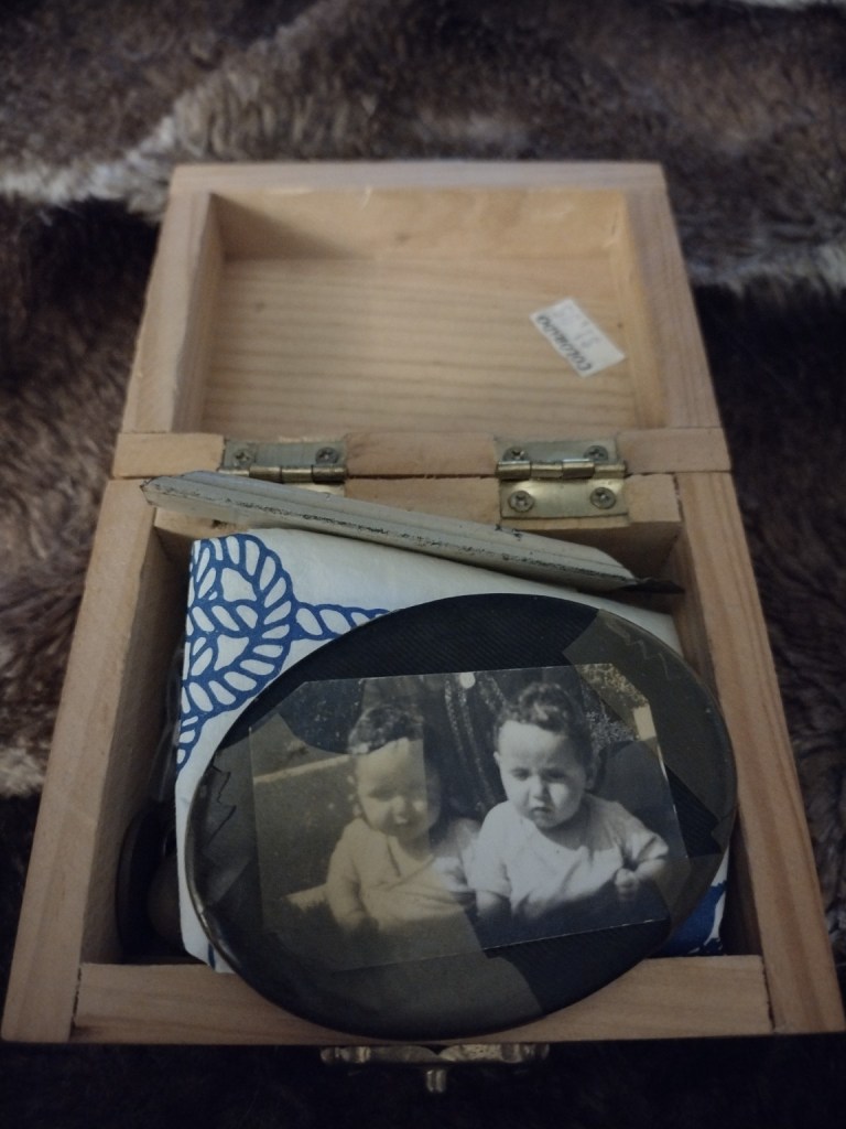 The open wooden keepsake box containing a sepia photograph, jewelry, coins, and small sentimental items.
