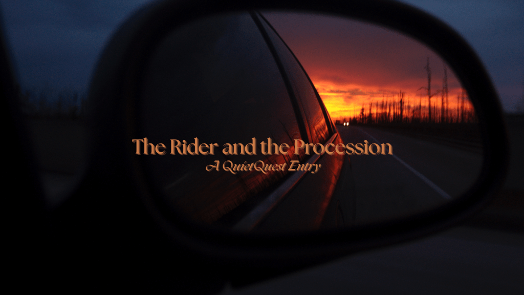 Rearview mirror view of a road at dusk, with glowing headlights visible behind the vehicle and a vivid orange sunset in the distance.