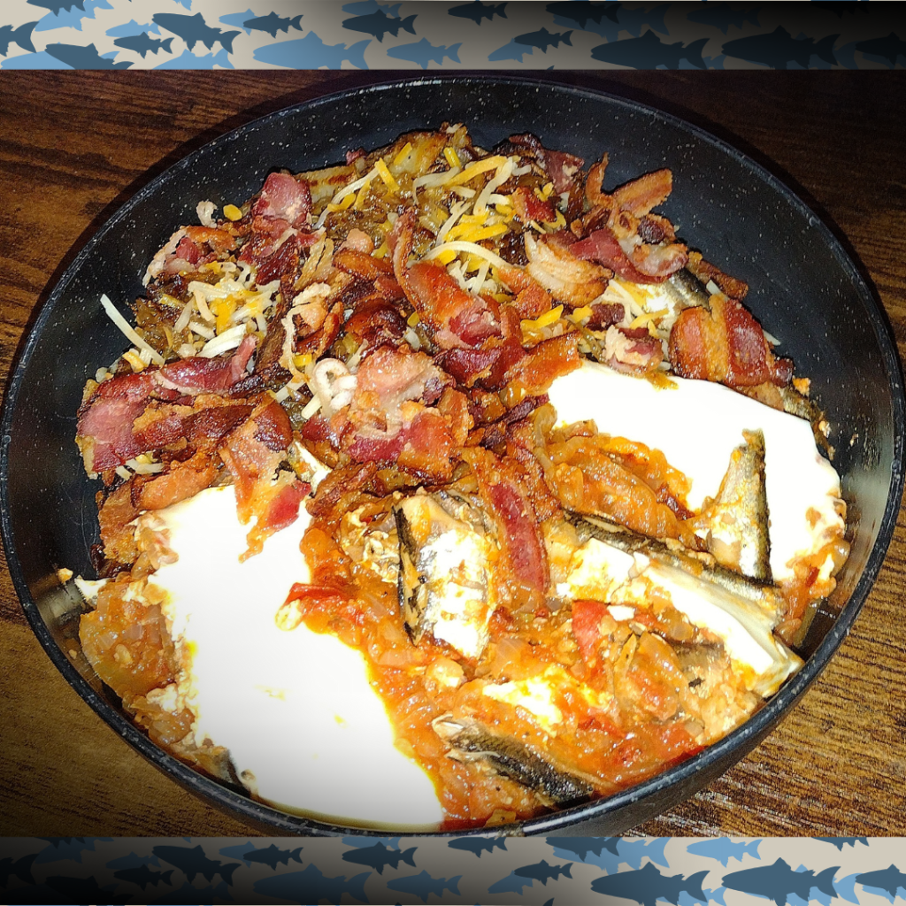 Sardine alchemy skillet with smashed tomatoes, soft eggs, bacon, and cheese.
