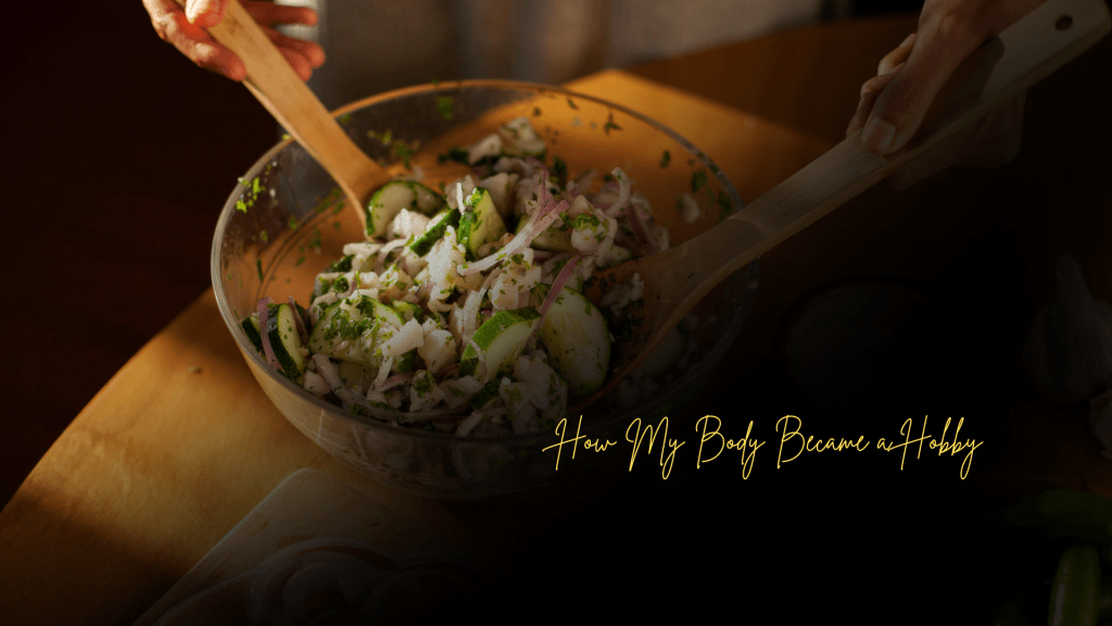 Hands mixing a fresh vegetable salad in a glass bowl on a wooden table, with the overlay text “How My Body Became a Hobby.”