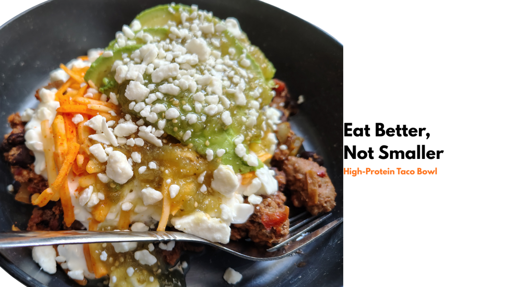 Feature image for a high-protein taco bowl post showing a bowl topped with avocado, salsa verde, cottage cheese, shredded cheese, and feta, with overlay text reading “Eat Better, Not Smaller: High-Protein Taco Bowl.”