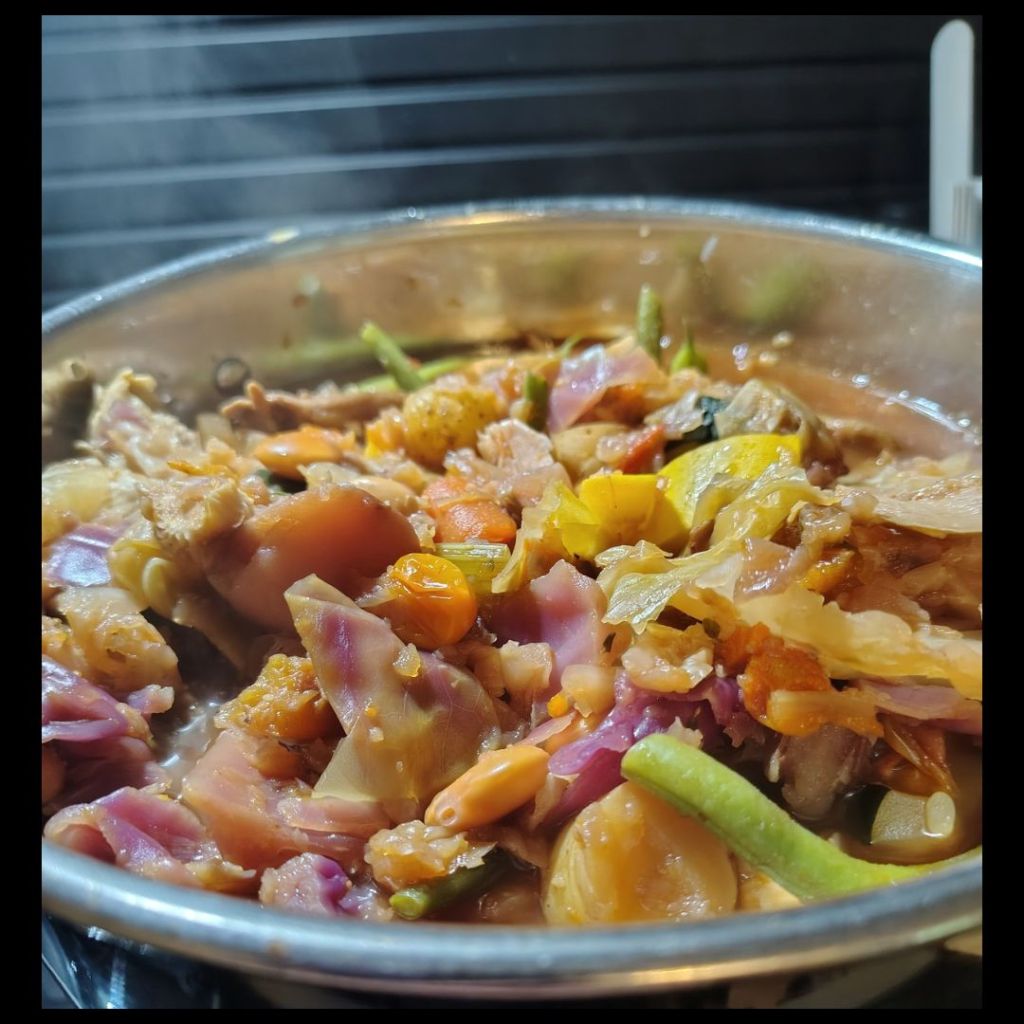 Cherry Soup simmering in a large stockpot as fresh vegetables, mushrooms, herbs, and broth cook together into a hearty late summer vegetable soup.