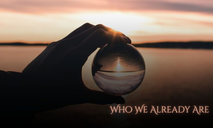 A silhouetted hand holds a clear glass sphere at sunset over calm water, with the horizon and sunlight refracted through the sphere. The title "Who We Already Are" appears in the lower right.