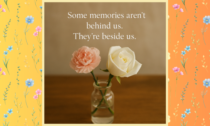 A digital image featuring a clear glass vase holding two flowers—a soft pink carnation and a creamy white rose—set on a wooden surface with warm natural lighting. The background is a soft beige, and the photo is framed by floral-patterned side borders in yellow and orange tones. Centered above the flowers is the quote: “Some memories aren’t behind us. They’re beside us.”
