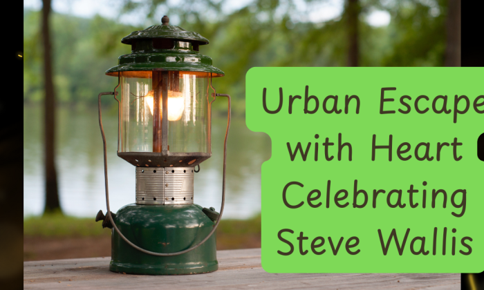 A vintage green camping lantern lit with a warm glow sits on a wooden surface outdoors, with a serene lake and trees in the background. To the right, a rounded green text box reads: “Urban Escape with Heart Celebrating Steve Wallis.”